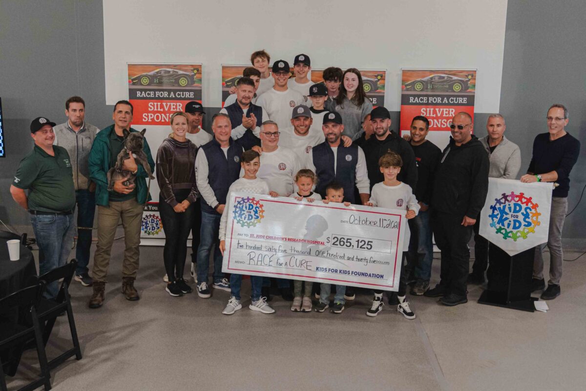 A group poses with a large charity check for $265,125.00